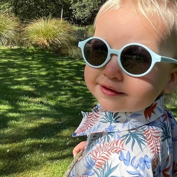 Blue Breeze Baby Sunglasses with detachable rubber head strap. Round Frames. For babies 6M-3Y old. Image depicts blonde 1.5YR old wearing the blue sunglasses.