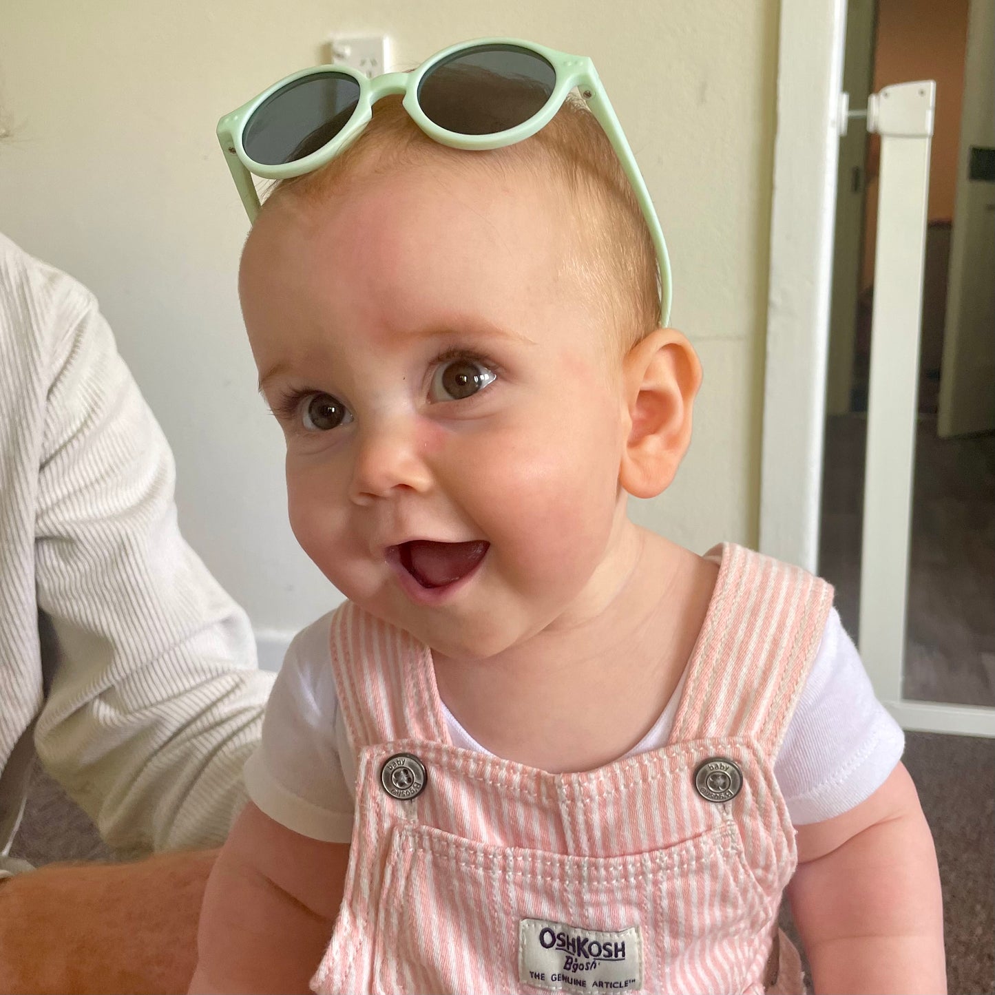 Fresh Mint Baby Sunglasses with detachable rubber head strap. Round Frames. For babies 6M-3Y old. Image depicts baby girl wearing the White sunglasses.