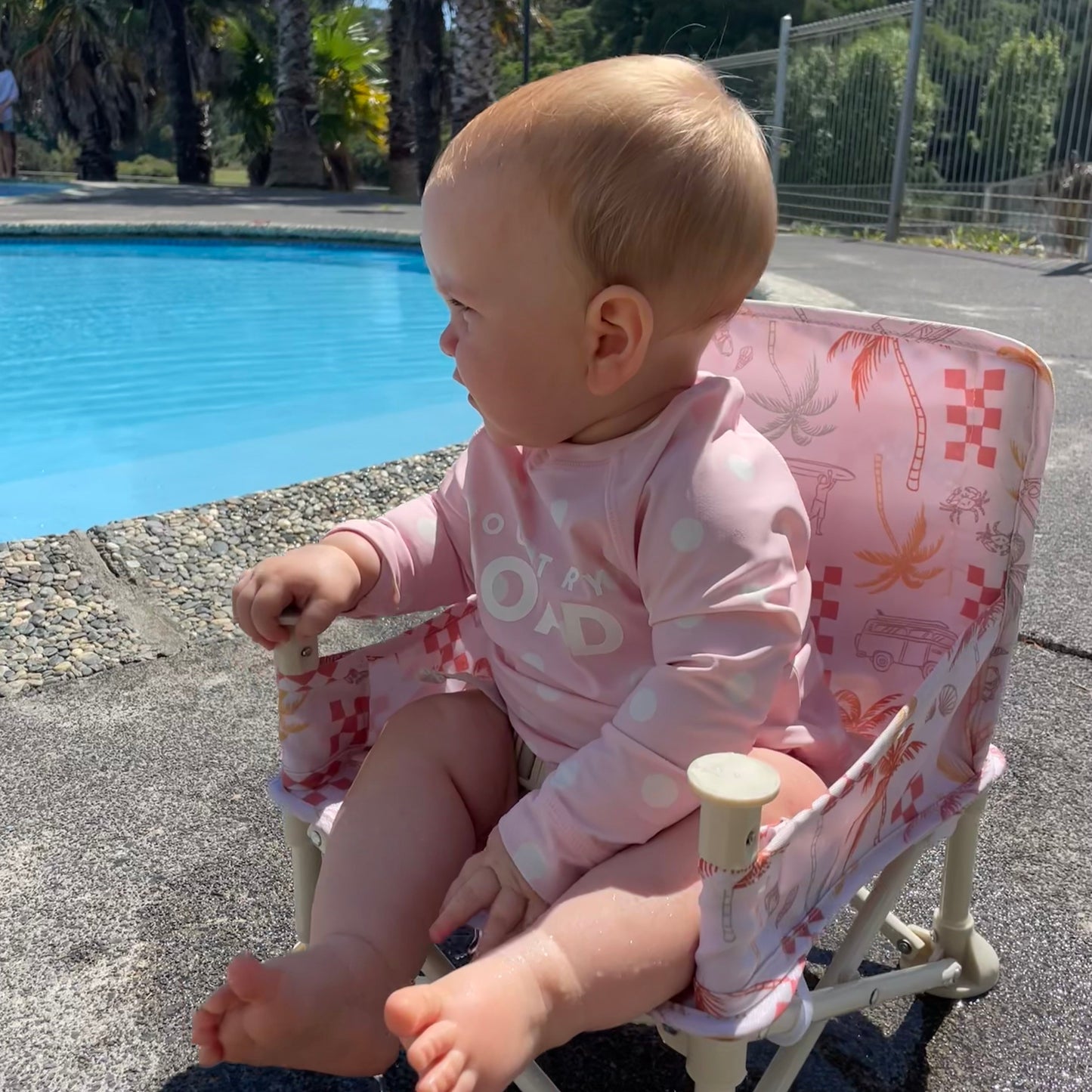The Coastal patterned Sunkissed Portable Highchair side view with a baby girl. For ages 6M-3Y old.